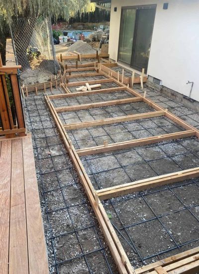 Construction of a wooden deck frame in progress outside a house.