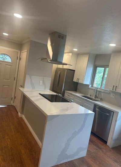 Contemporary kitchen with white cabinets, marble countertops, and stainless steel appliances.
