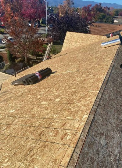 Roof installation in progress with plywood sheathing and tools on the roof.